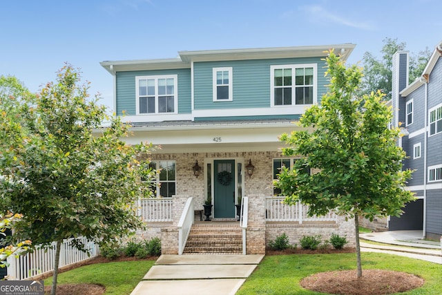 view of front of house featuring a porch, fence, and brick siding