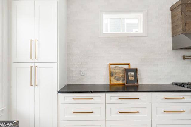 room details featuring dark countertops, decorative backsplash, and white cabinetry