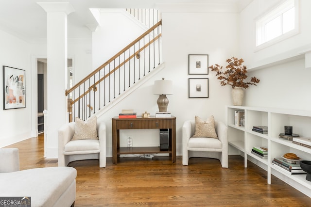 living area featuring baseboards, stairs, ornate columns, and wood finished floors