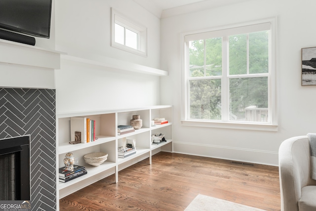 interior space with baseboards, visible vents, a tiled fireplace, and wood finished floors