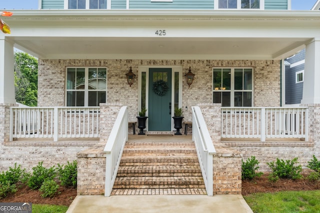property entrance featuring a porch and brick siding