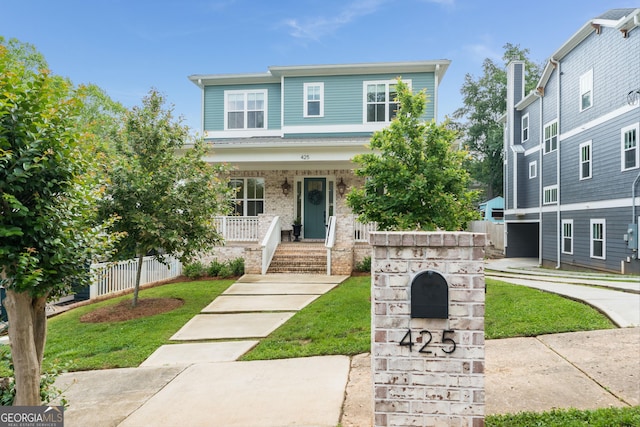 view of front of property with covered porch, brick siding, fence, and a front lawn