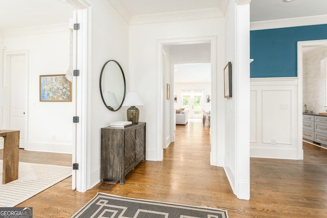 hall with ornamental molding and wood finished floors