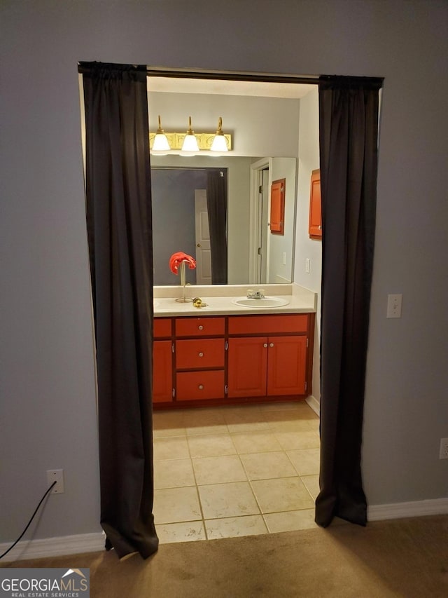 bathroom with double vanity, baseboards, a sink, and tile patterned floors