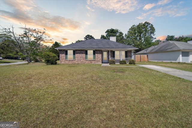 view of front of home with a porch, brick siding, a chimney, and a front lawn
