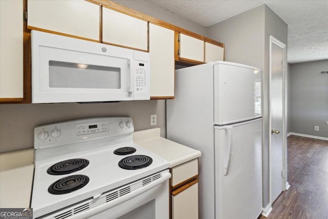 kitchen with white appliances, light countertops, a textured ceiling, white cabinets, and dark wood finished floors
