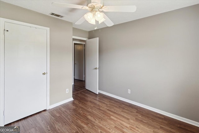 unfurnished bedroom with visible vents, a ceiling fan, baseboards, and wood finished floors