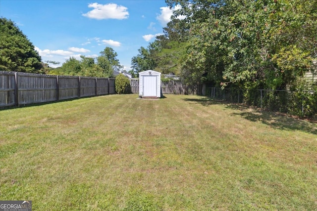 view of yard featuring an outbuilding, a fenced backyard, and a storage unit