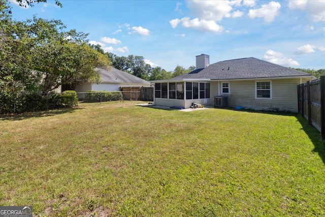 rear view of property featuring a lawn, central AC unit, a fenced backyard, and a sunroom