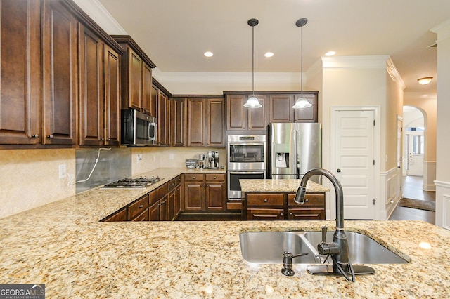 kitchen featuring dark brown cabinetry, appliances with stainless steel finishes, a sink, arched walkways, and ornamental molding