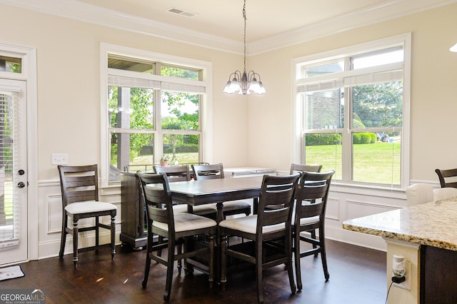 dining space featuring visible vents, crown molding, a decorative wall, dark wood-type flooring, and a chandelier