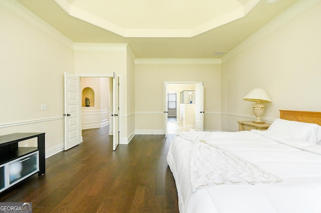 bedroom with crown molding, arched walkways, a raised ceiling, and wood finished floors