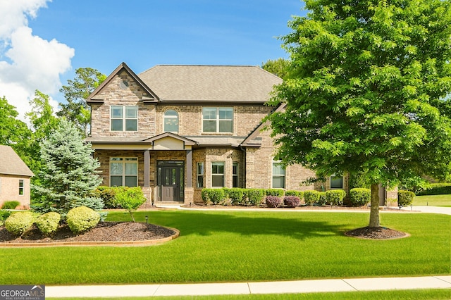 craftsman-style home with brick siding, a shingled roof, and a front yard