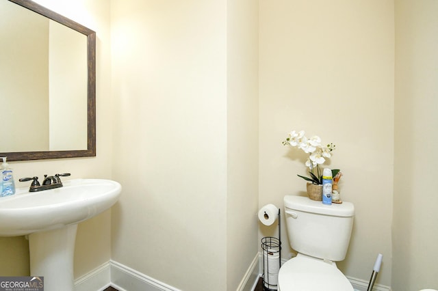 bathroom featuring baseboards, a sink, and toilet