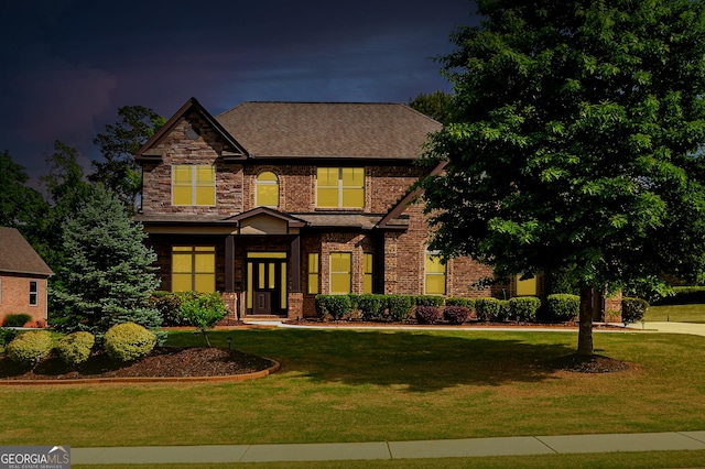 craftsman house featuring brick siding, a shingled roof, and a front yard