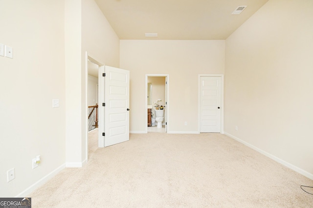 unfurnished bedroom with carpet floors, baseboards, and ensuite bath