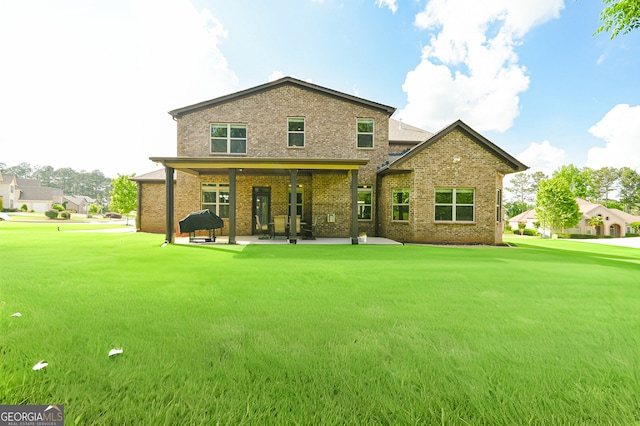 rear view of property with brick siding, a patio area, and a yard