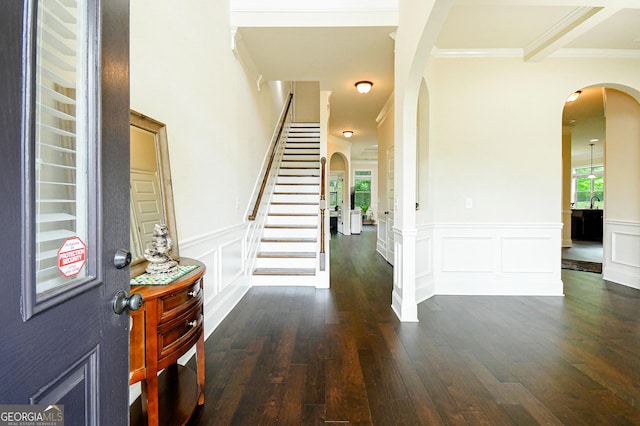 foyer featuring arched walkways, plenty of natural light, ornamental molding, and dark wood-type flooring