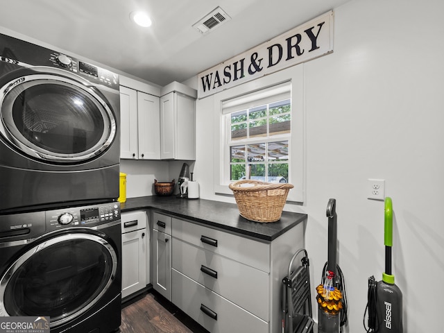laundry room with visible vents, stacked washer and clothes dryer, dark wood-style floors, recessed lighting, and cabinet space