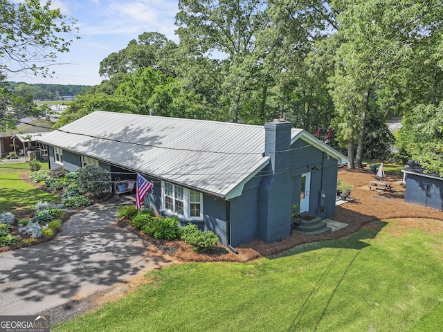 exterior space featuring a chimney, aphalt driveway, a front yard, and entry steps