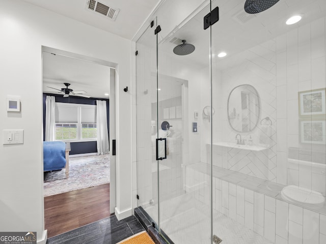 ensuite bathroom with ceiling fan, visible vents, wood finished floors, and a stall shower