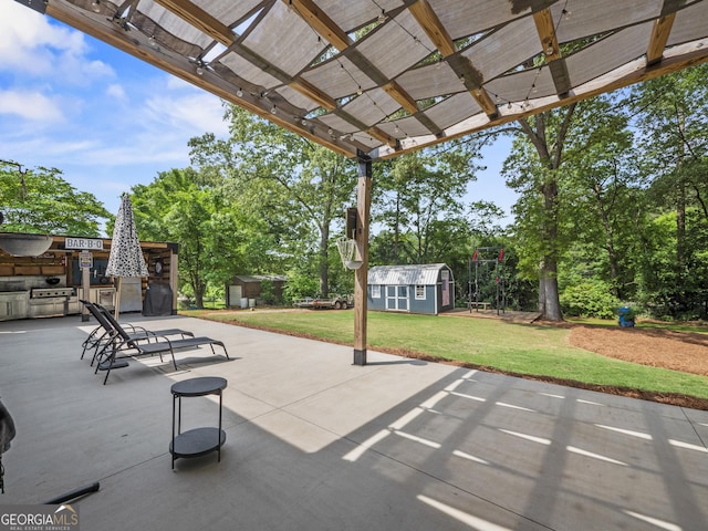 view of patio featuring an outdoor structure, a storage shed, a pergola, and an outdoor kitchen