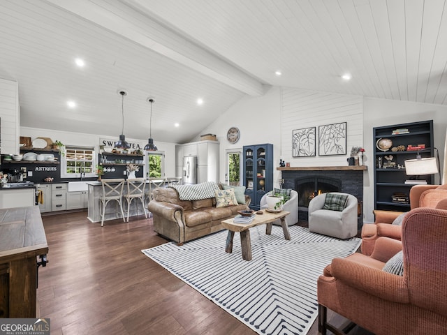 living area featuring recessed lighting, lofted ceiling with beams, a warm lit fireplace, and dark wood-style floors