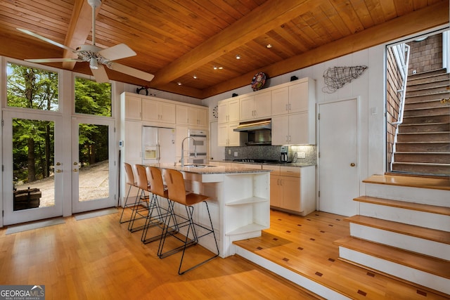 1006 Perrin Cove Rd, Tiger, GA 30576 - kitchen with under cabinet range hood, a ceiling fan, tasteful backsplash, light wood-style floors, and a wood ceiling with exposed beams