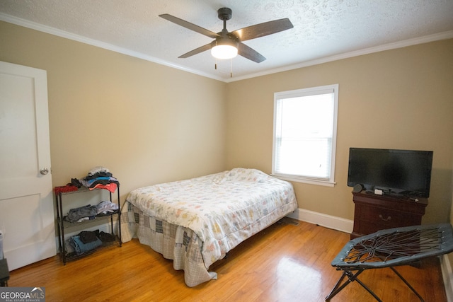 bedroom featuring ceiling fan, a textured ceiling, baseboards, light wood finished floors, and ornamental molding