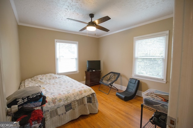 bedroom featuring crown molding, a textured ceiling, baseboards, and light wood-style flooring