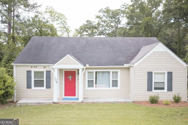 view of front facade with a shingled roof and a front lawn