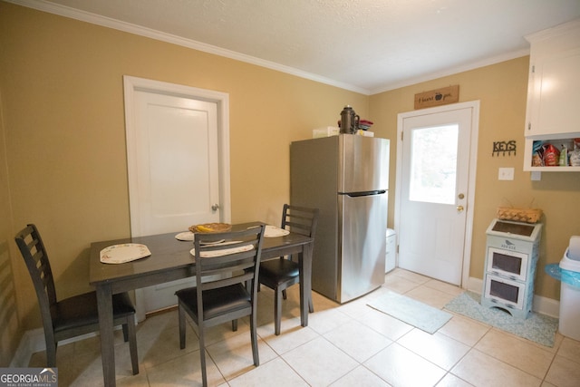 kitchen with crown molding, white cabinets, freestanding refrigerator, baseboards, and light tile patterned floors