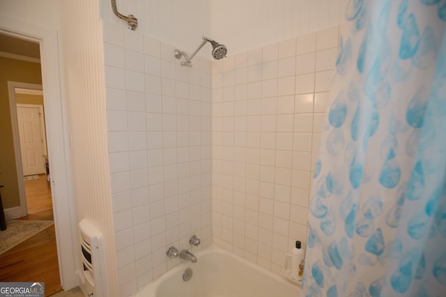 full bathroom with crown molding, shower / bath combo with shower curtain, and wood finished floors