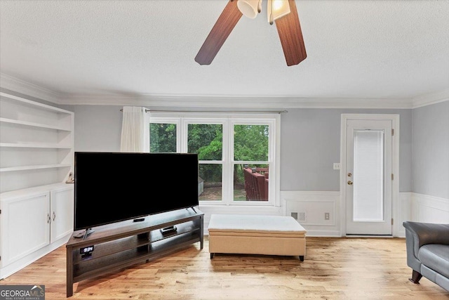 living area with wainscoting, a ceiling fan, a textured ceiling, and visible vents