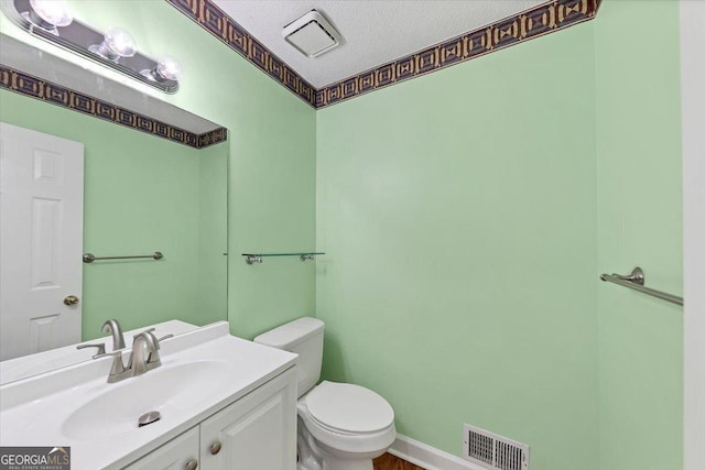 half bath with visible vents, a textured ceiling, toilet, and vanity