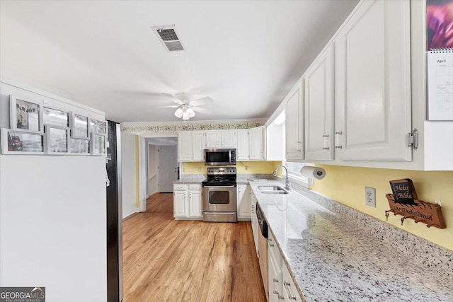 kitchen featuring a ceiling fan, visible vents, a sink, stainless steel appliances, and white cabinetry