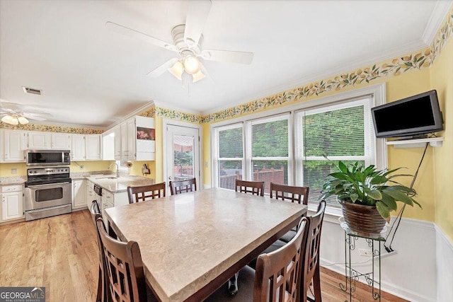 dining room with visible vents, ornamental molding, ceiling fan, and light wood-type flooring