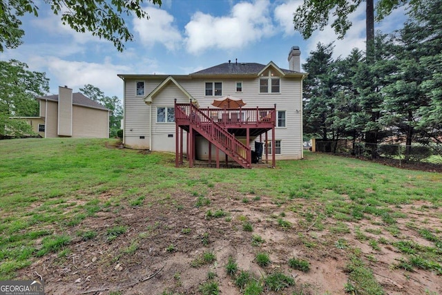 back of property with fence, a deck, a lawn, and stairway