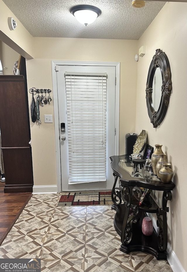 entryway with a textured ceiling, baseboards, and wood finished floors