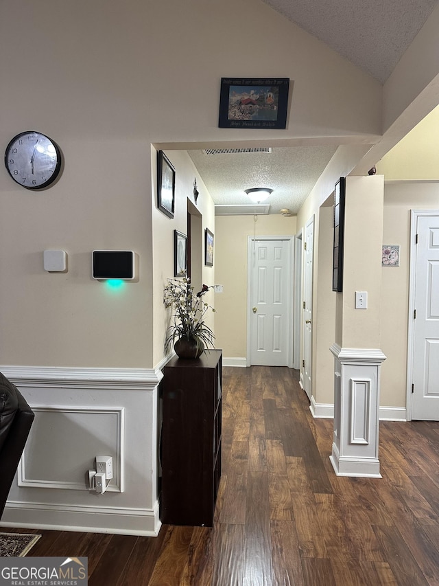hall with a textured ceiling and dark wood-style flooring