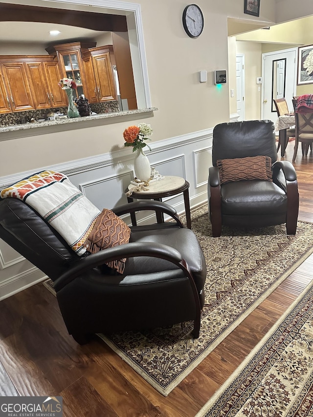 sitting room with wainscoting, wood finished floors, and a decorative wall