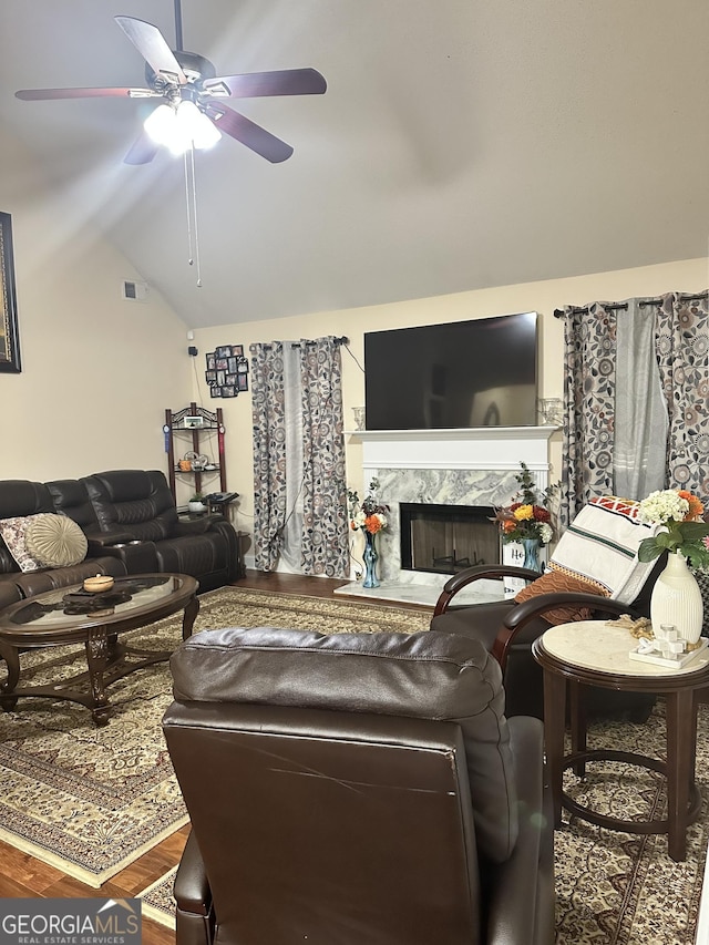 living room featuring a premium fireplace, a ceiling fan, wood finished floors, lofted ceiling, and visible vents