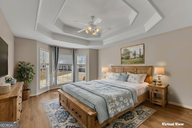 bedroom featuring crown molding, baseboards, a raised ceiling, and light wood-type flooring