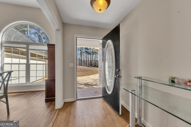 foyer entrance with baseboards, light wood-style flooring, and washer and dryer