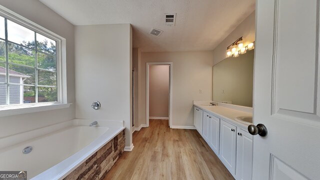 8256 Milam Loop, Fairburn, GA 30213 - full bath featuring double vanity, a garden tub, wood finished floors, and visible vents