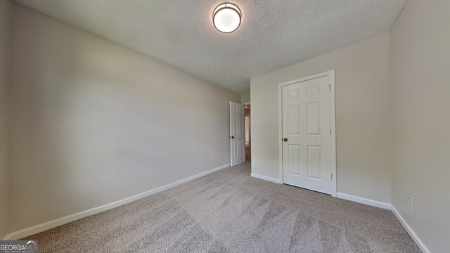 8256 Milam Loop, Fairburn, GA 30213 - unfurnished bedroom featuring baseboards, a textured ceiling, and carpet