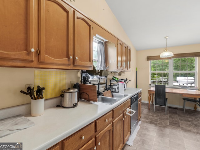 kitchen featuring hanging light fixtures, a sink, light countertops, brown cabinetry, and vaulted ceiling