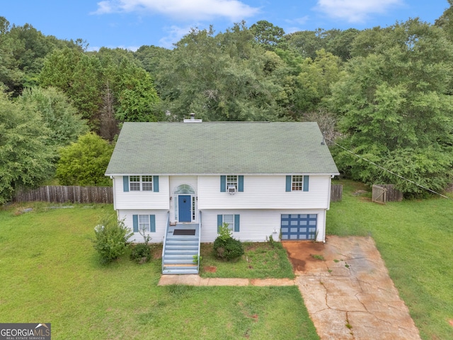 raised ranch featuring a garage, fence, concrete driveway, and a front yard