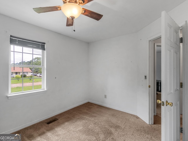 carpeted spare room featuring ceiling fan, visible vents, and baseboards