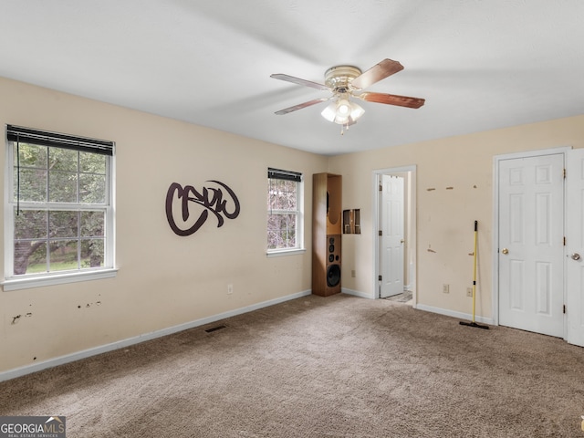 empty room with baseboards, a ceiling fan, carpet flooring, and visible vents